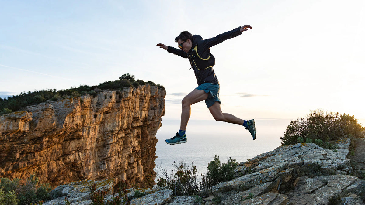 Trail runner leaping across a clifftop ridge high in the French mountains