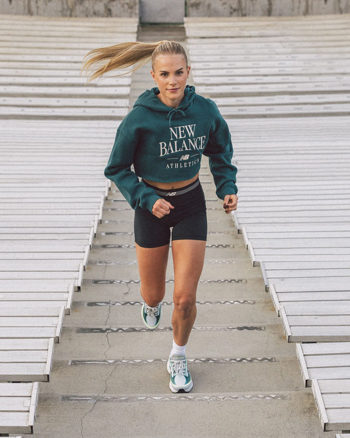 Runner in a New Balance hoodie and shoes running up stadium steps