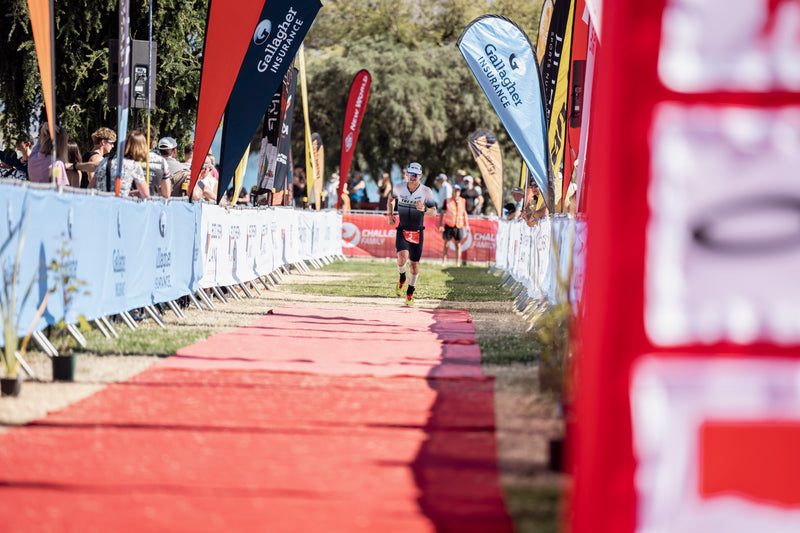 A Challenge Wānaka athlete running down the red carpet to the finish line