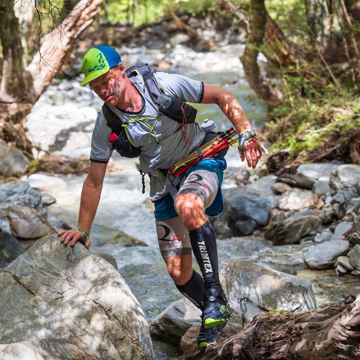 Ian trail running through a rocky stream during an ultra race.