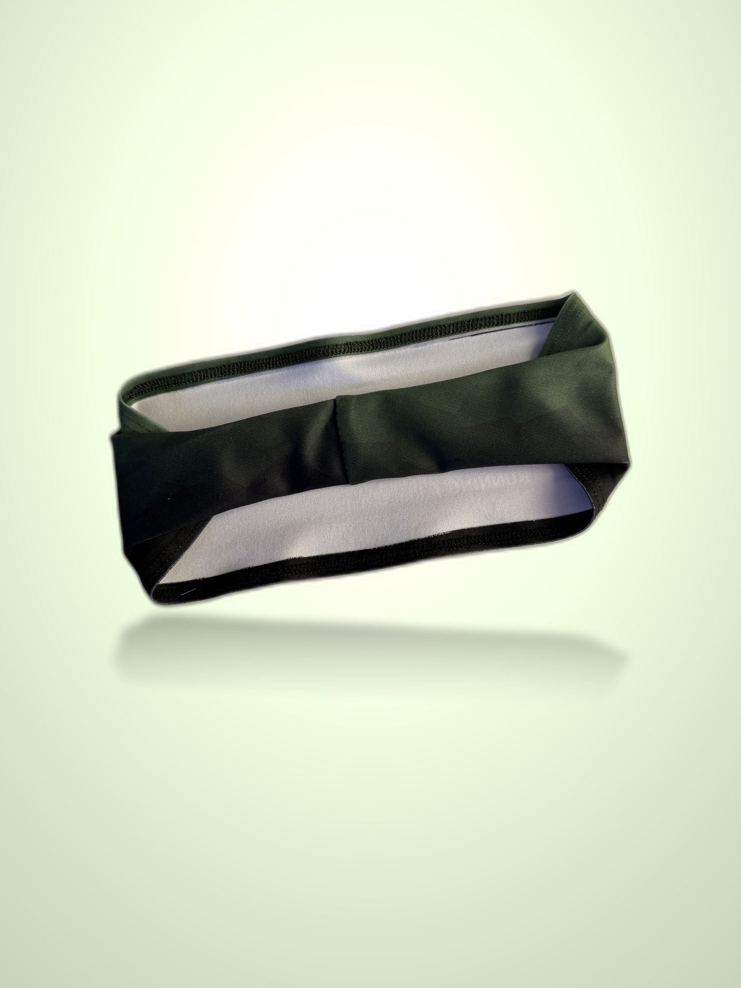 A dark olive green fabric headband with a white inner lining, shown floating against a light green gradient background with a soft reflection underneath.