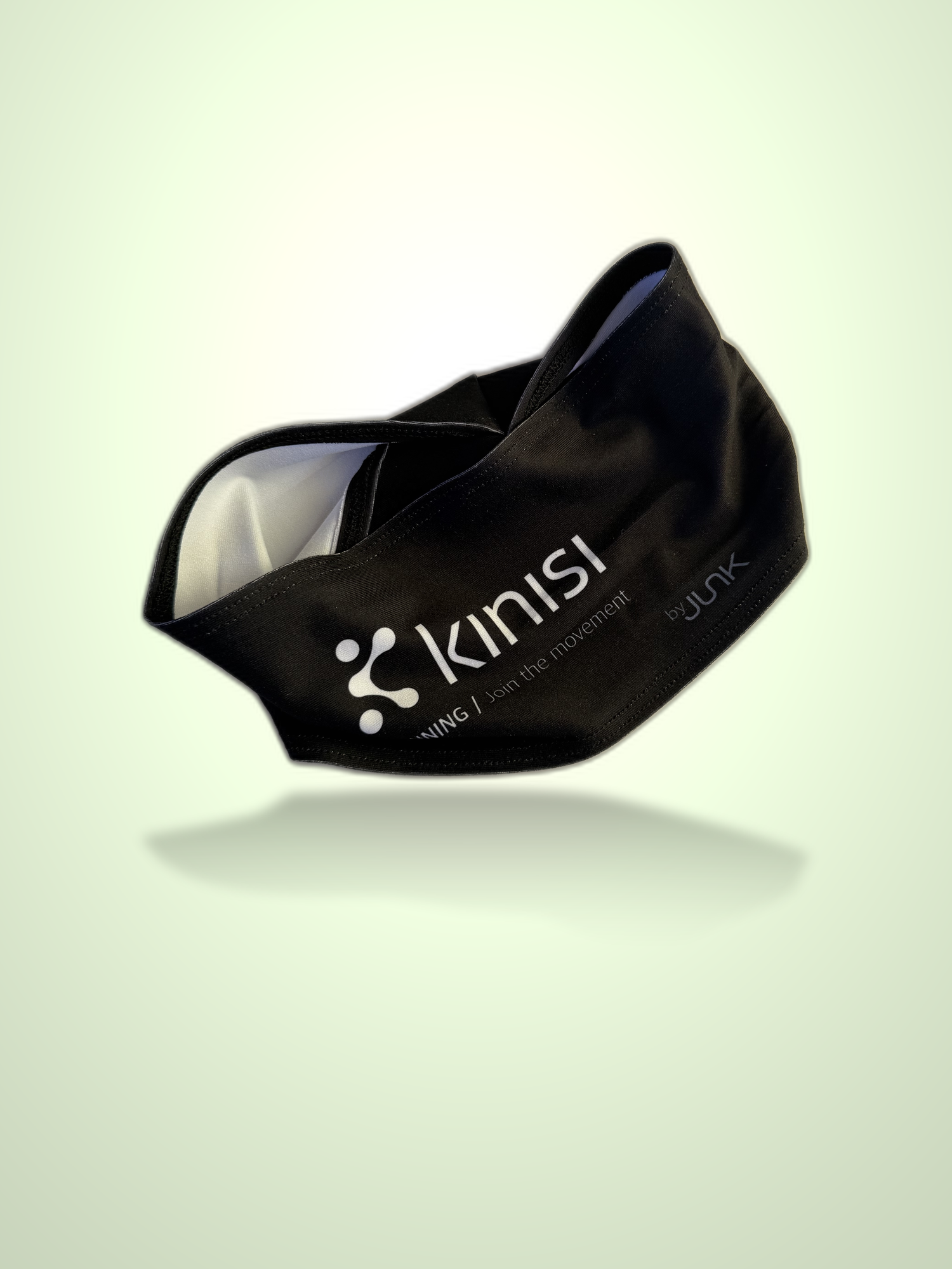 A black athletic headband with white printed Kinisi Running branding and text, shown floating against a pale green gradient background with a soft reflection underneath.