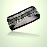 A black athletic headband with a green stripe and a white mountain pattern, shown floating against a pale green background.