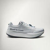A light gray and white Mount to Coast running shoe shown from the side against a clean, light gray studio background.