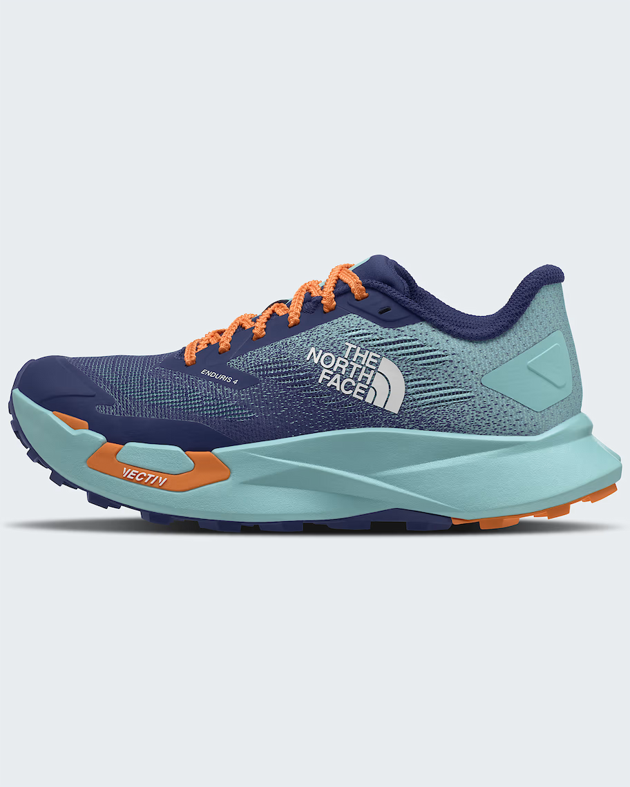 A side profile view of The North Face Vectiv Enduris 4 trail running shoe. The shoe features a dark navy blue mesh upper, a light teal-green midsole and heel counter, and bright orange accents on the laces, logo, and 'Vectiv' text on the forefoot.