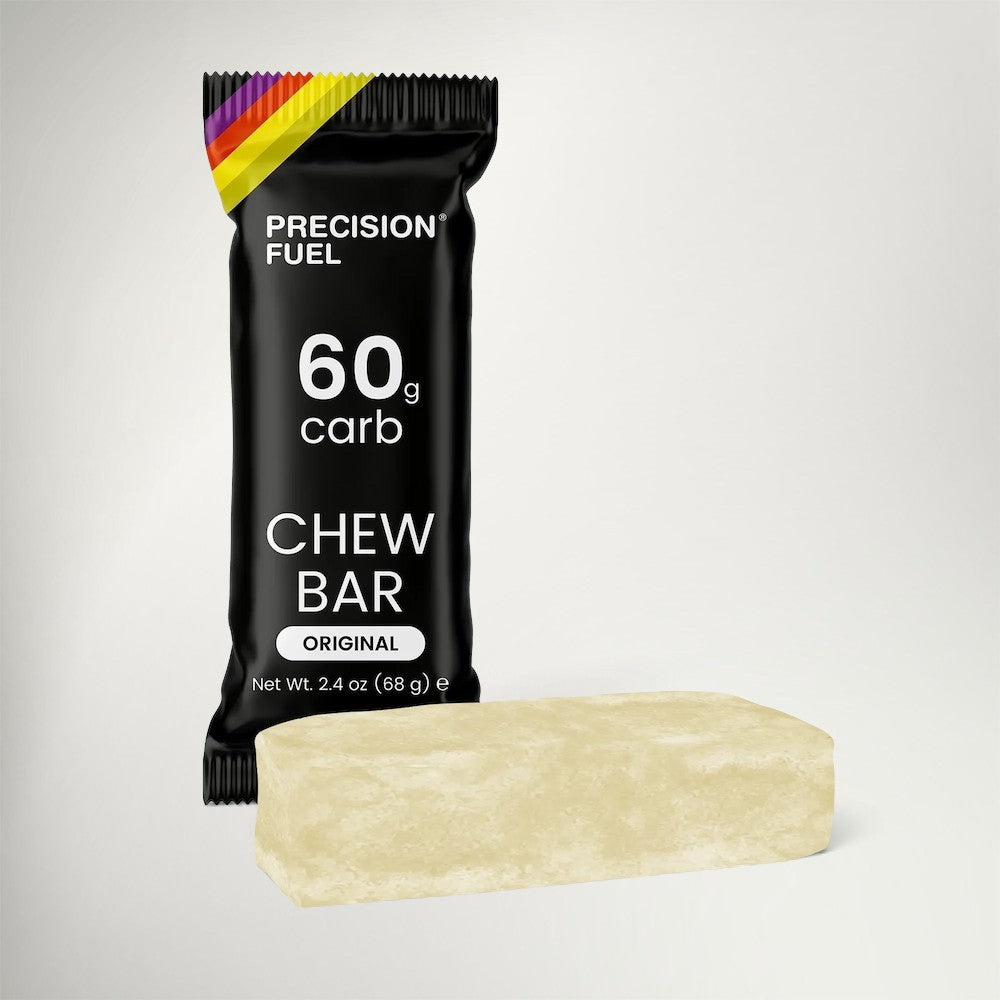 A Precision Fuel Chew Bar in its black wrapper, shown with the unwrapped pale beige chew bar in front on a light gray background.