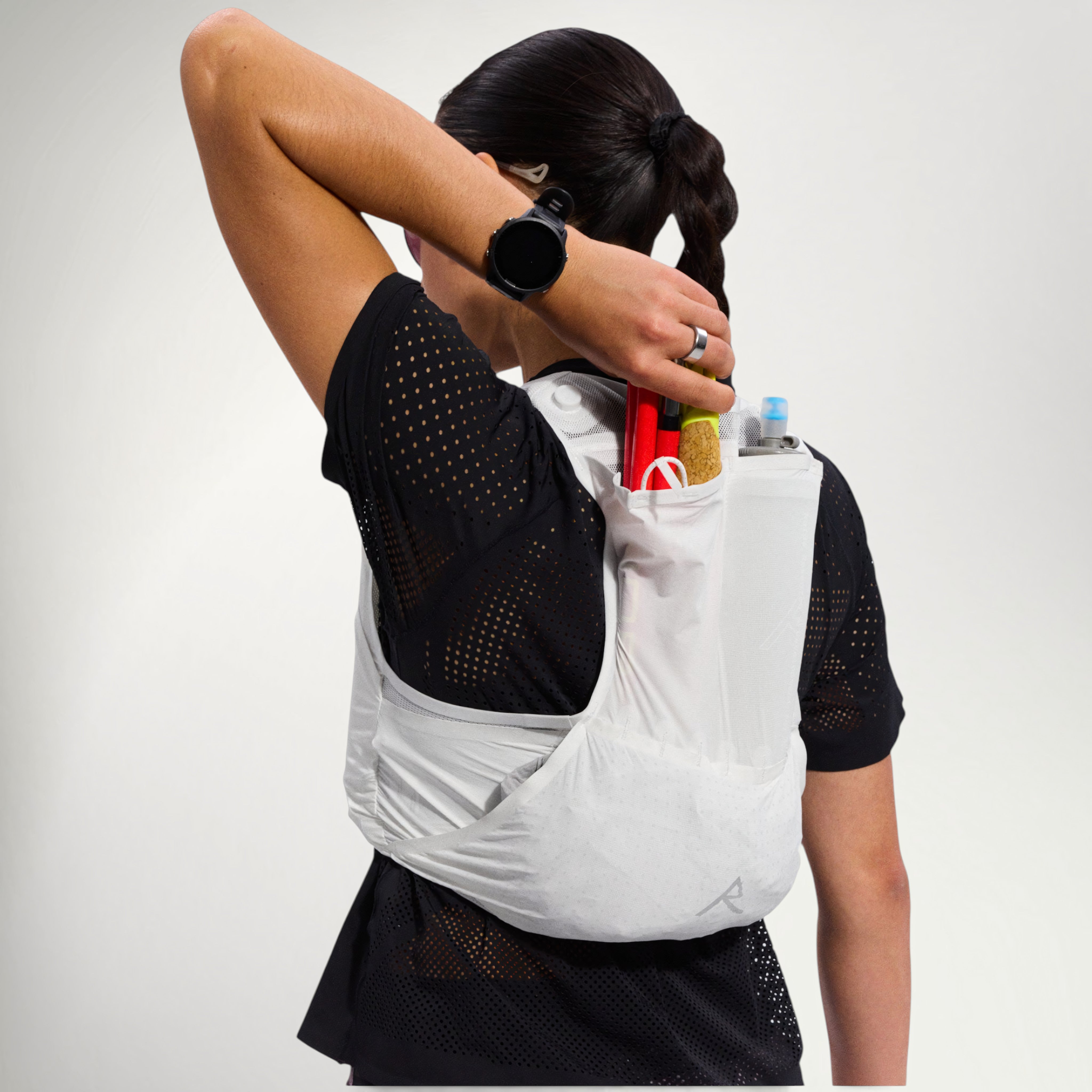 Runner reaching into the back pocket of the Raide LF 5L Running Vest