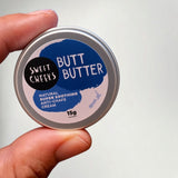 Hand holding a Sweet Cheeks Butt Butter 15g pocket tin of anti-chafe cream