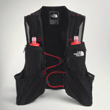 The North Face Summit Series Run Vest 10 in Black, front view with two red-capped soft flasks and red bungee sternum straps