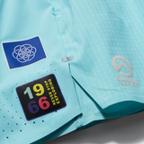 Close-up of a light aqua running jacket showing the textured fabric, a blue circular logo patch, a black rectangular '1966 Explorers' patch, and a silver 'Summit Series' logo.