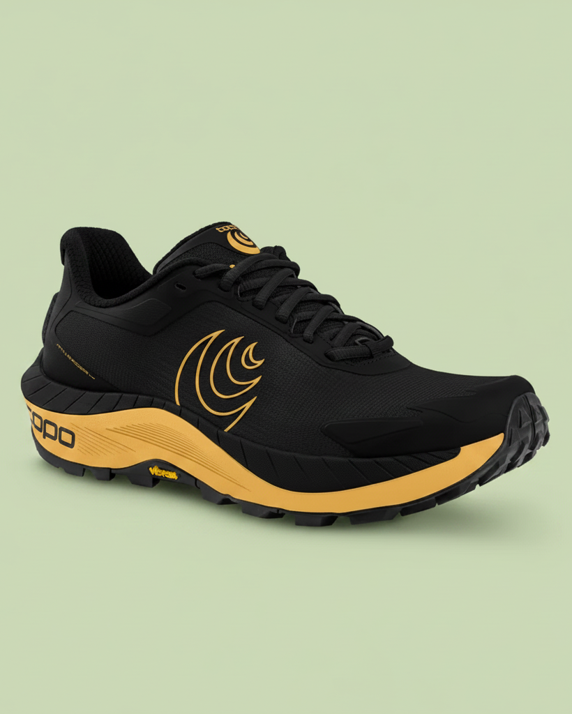 Black and yellow Topo running shoe on a pale green background.