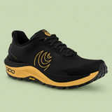 Black and yellow Topo running shoe on a pale green background.