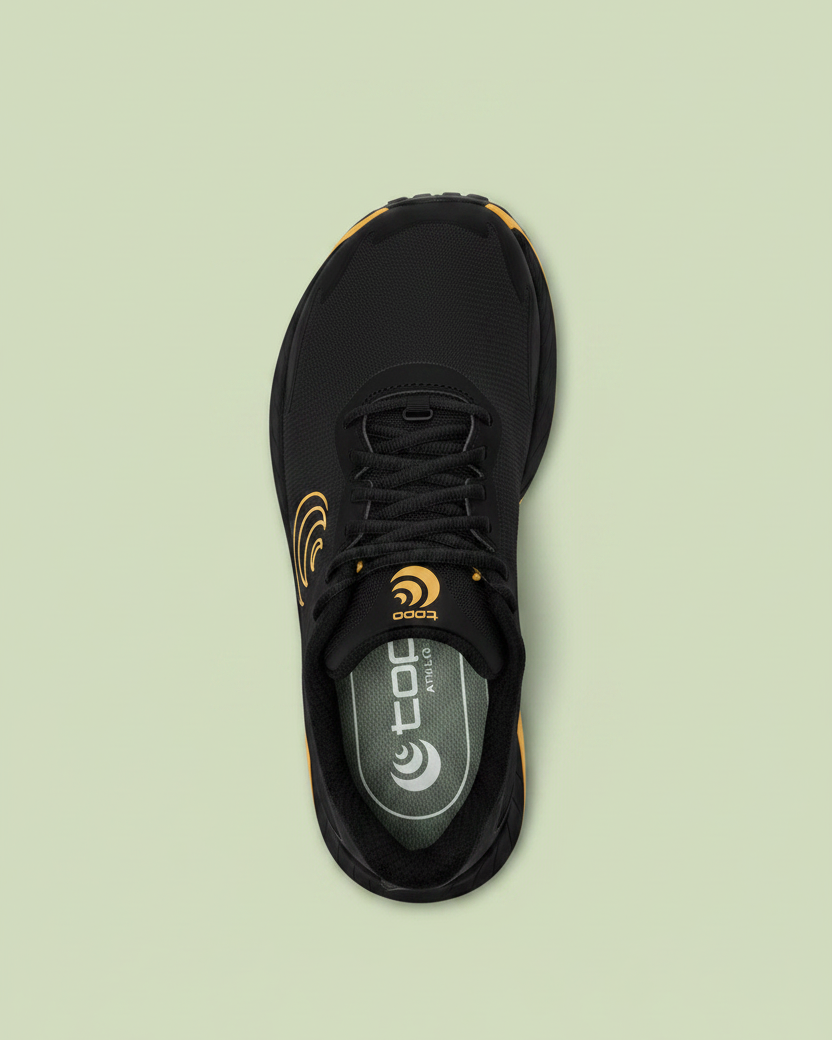 Black Topo running shoe with orange accents on a white background