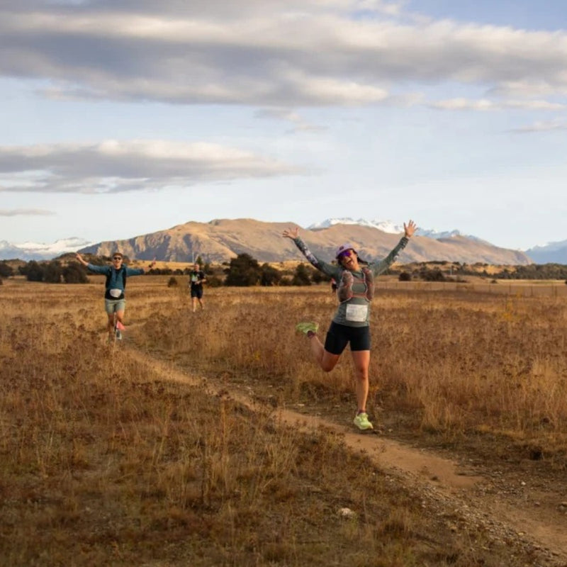 A runner celebrating on a golden tussock trail during Ultra Wānaka