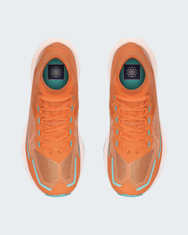 A pair of TNF orange athletic sneakers shown from a top-down view on a light gray background. The shoes feature a textured knit upper, matching orange laces, and light blue accents along the sides and around the eyelets.