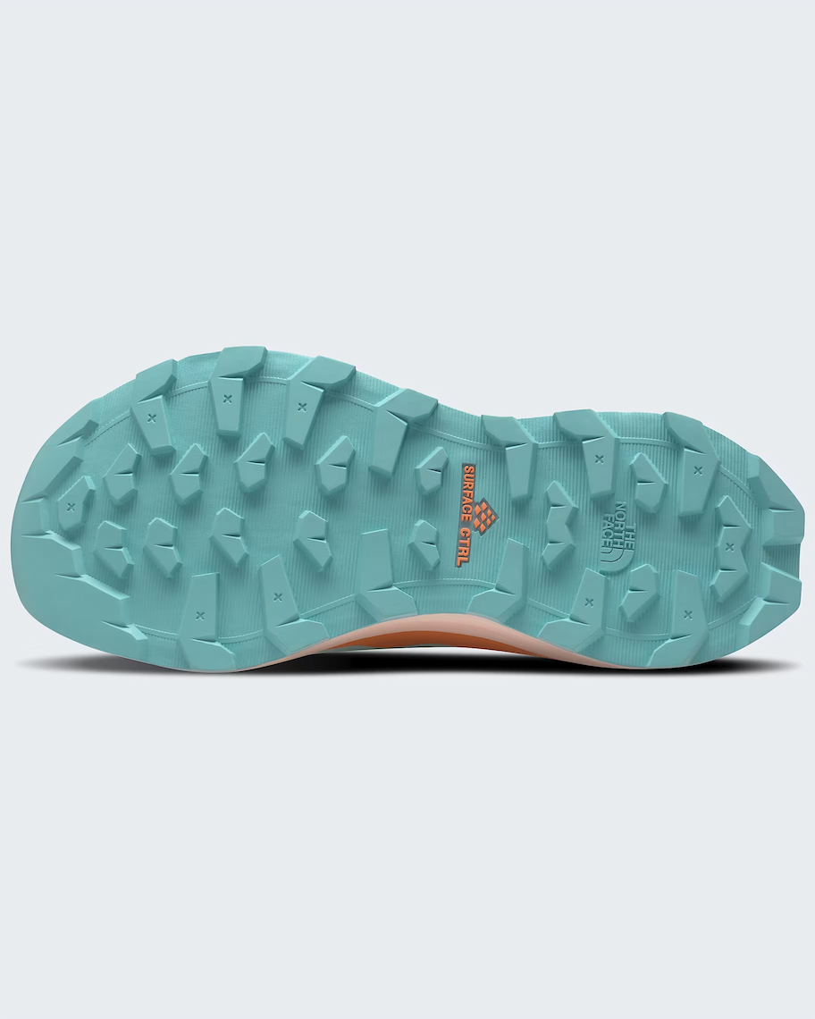 The rugged outsole of TNF trail running shoes in a light teal blue-green color, featuring deep lugs and a small orange 'Surface CTRL' logo, shown against a light gray background.