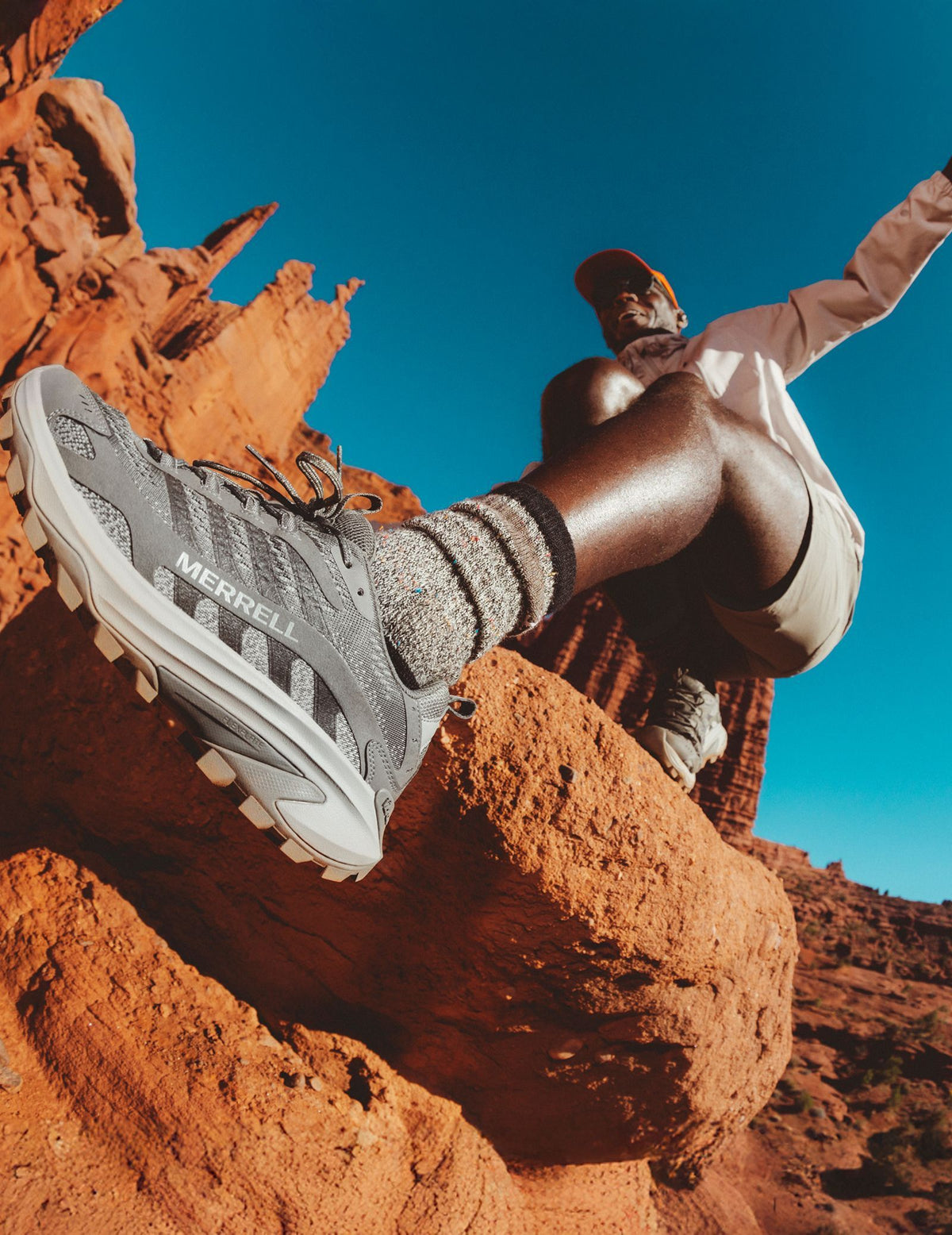 Close-up of a Merrell trail shoe as a hiker climbs over red desert rock